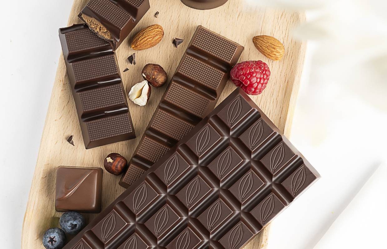 Tablettes et chocolats belges Choc and Co sur une planche en bois avec amandes, noisettes et framboise